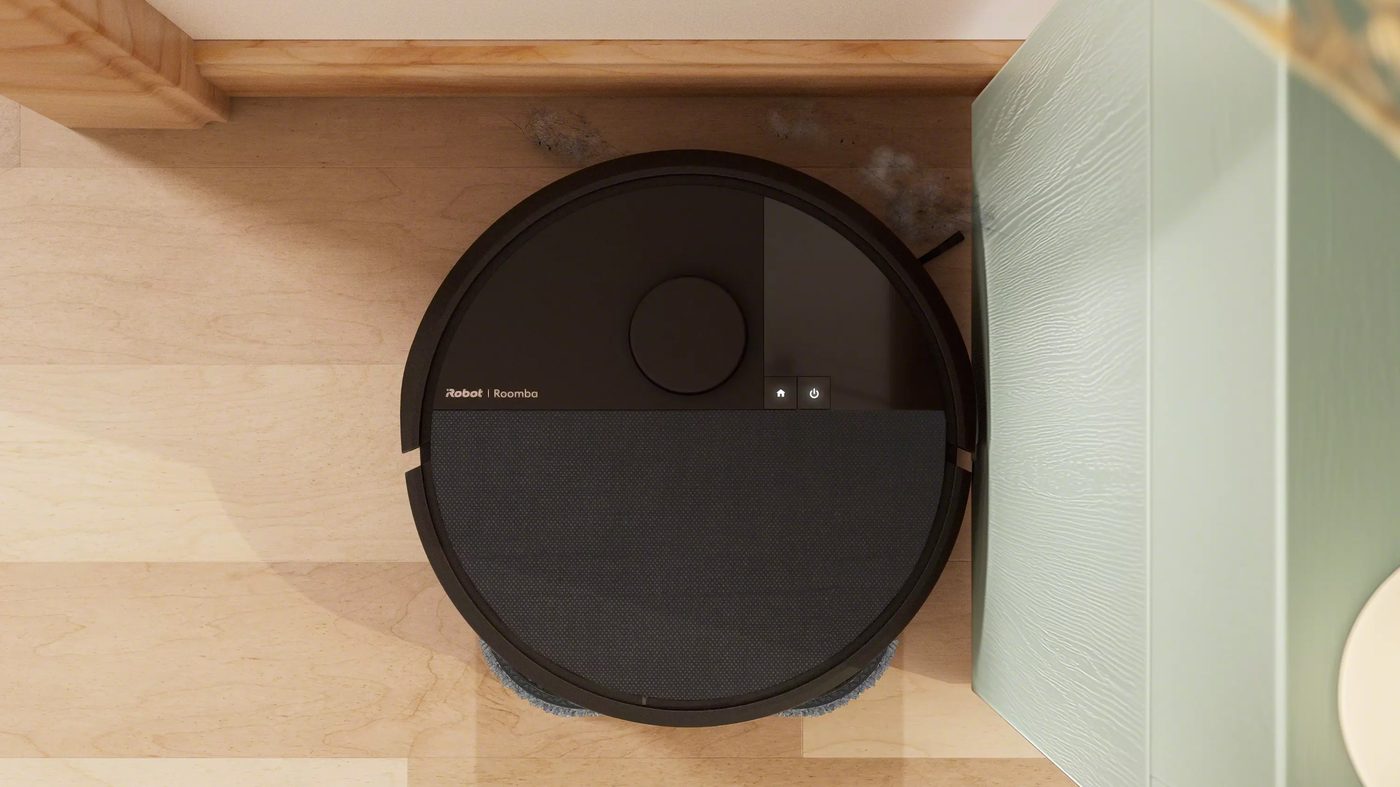 Roomba Plus 505 Combo extending mop pad reaching into a kitchen corner along the baseboard